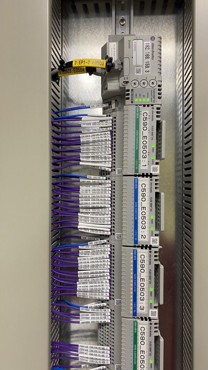 Close up of a PLC input and output rack with numbered purple cables and labelled terminal markers
