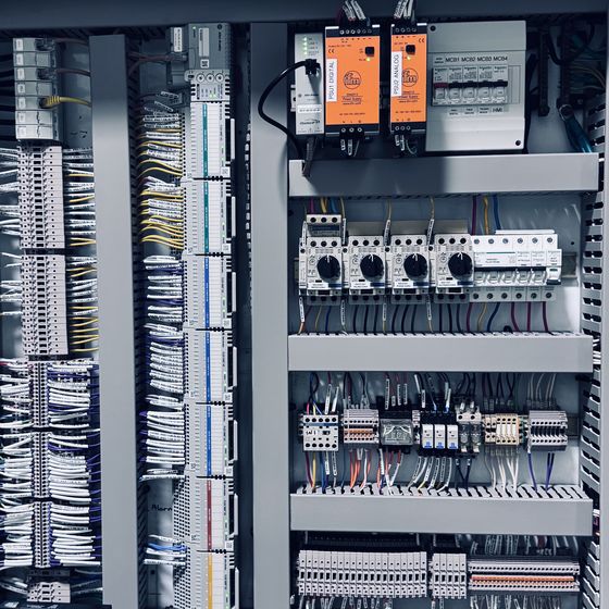 Motor protection breakers, contactors and two orange power supplies on DIN rail inside an industrial control cabinet