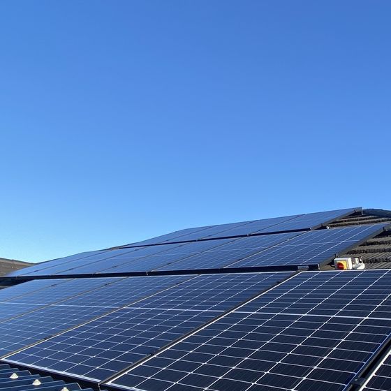 Solar panels across a pitched roof under a deep blue sky